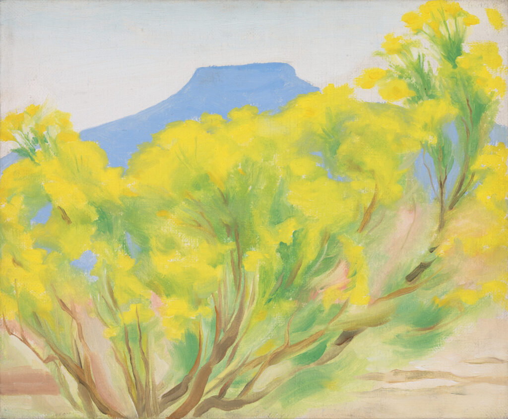 A cottonwood tree thick with yellow leaves fills the foreground. The top of Pedernal, visible in the distance, peeks out above the trees.