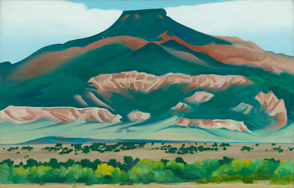 Oil painting of Pedernal in fall, predominantly in dark greens and oranges with brush in foreground.