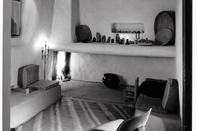 A photograph of Georgia O'Keeffe's home and studio. In the background there are banco shelves built into the adobe with various tschockes placed on the shelves.