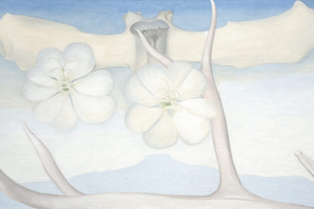 Large horizontal painting of blue and grey tones. Along the bottom in the foreground lies a bleached antler with arms reaching upward towards the sky. Floating along the top spanning the length of the canvas is a vertebral bone. Superimposed over this in the middle are two white flowers, hovering just above a blue silhouette of the Pedernal.