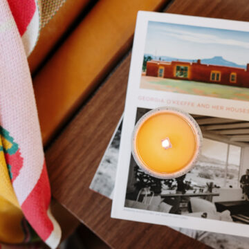 A lit candle is stacked on top of books next to a couch