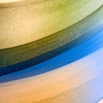 Curved lines of glass in shades of green, blue, and yellow.