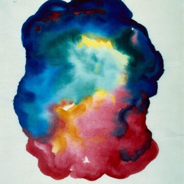 An amorphous blob of flowing blue, green, and red paint occupies the center of the paper. Patches of yellow dot the image. The form resembles a dark, colorful cloud, and contrasts with the plain white paper framing it.