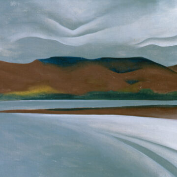 A lake with a white beach stretches across the foreground of the work. In the distance, brown and green mountains rise against a gray sky filled with rippling clouds.