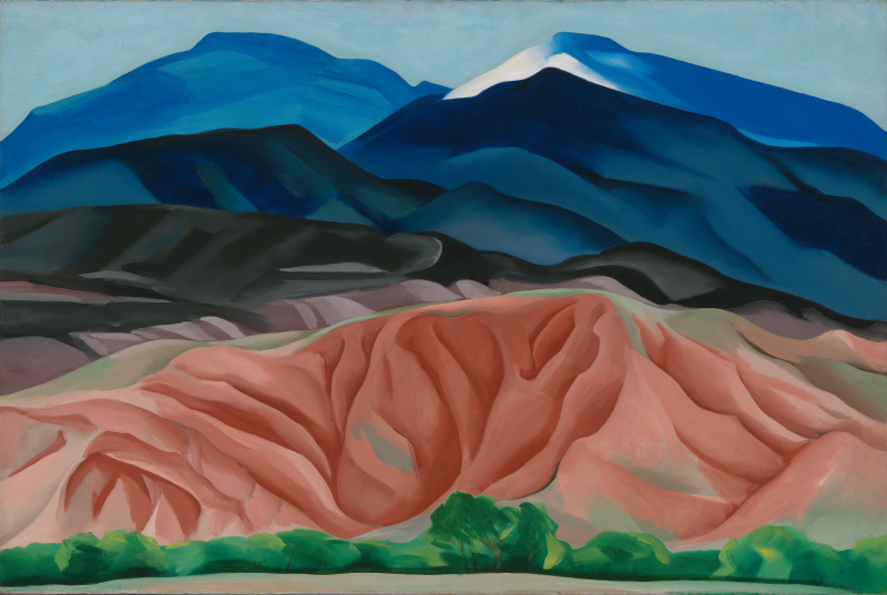 Horizontal landscape with blue peaks in the background, black and pure ground. Along the bottom edge is a strip of green foliage and trees.