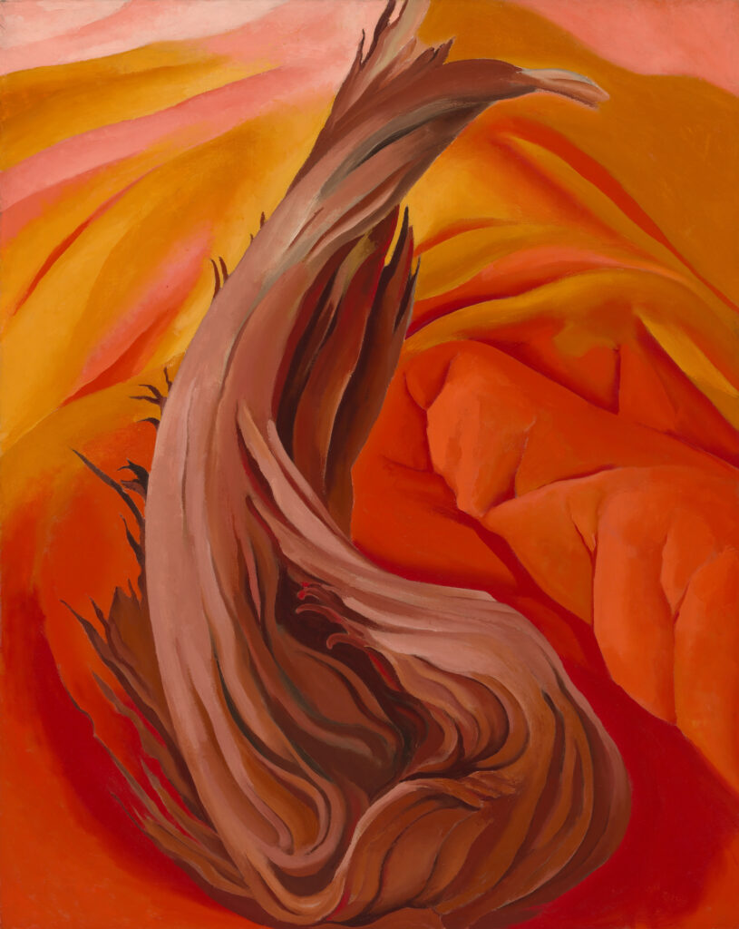 Vertical canvas of vibrant red and orange hills dominated in the foreground by a twisting frayed brown tree stump - a piece of driftwood in a sea of reddish orange.