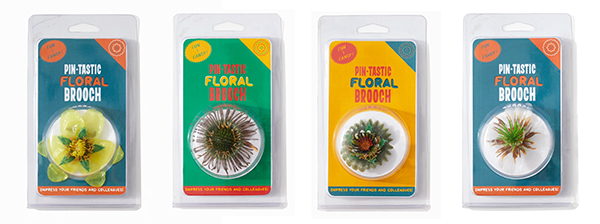 Photograph of four colorful packages holding floral brooches made out of plastic. 