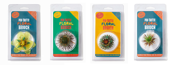 Photograph of four colorful packages holding floral brooches made out of plastic.