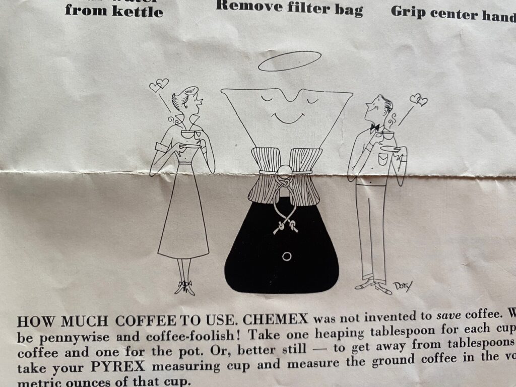 A close-up photograph of an illustration of two people standing on either side of a Chemex with instructions on how much coffee to use.