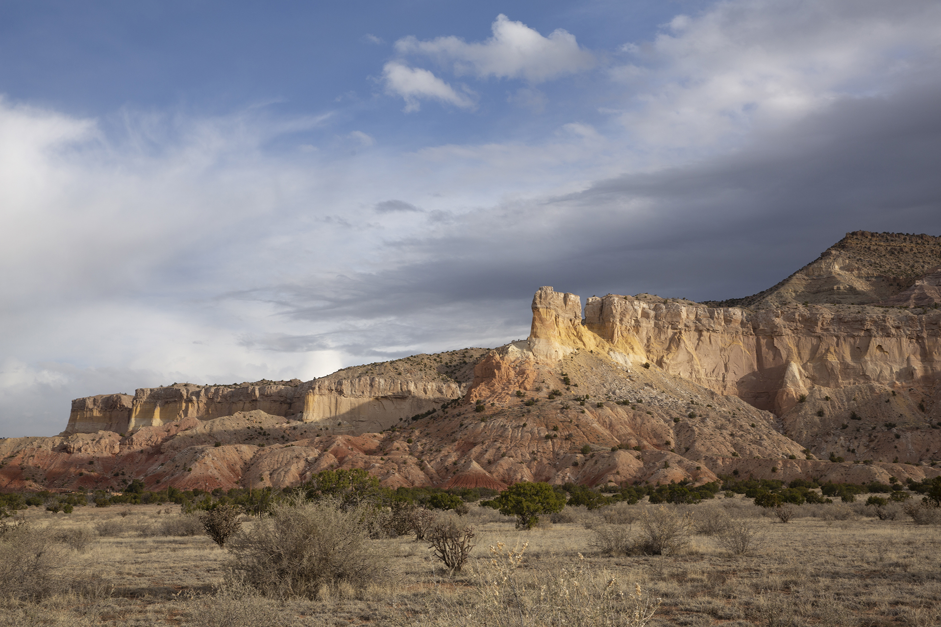 Photograph of a Mesa and desert landscape with clouds above.