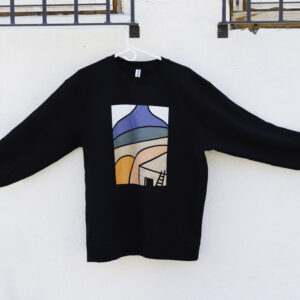 A black sweatshirt hanging with a simple modern design of a desert landscape and adobe home in shades of blue, beige, green, and orange.