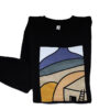 Photograph of a black sweatshirt with a simple modern design of a desert landscape and adobe home in shades of blue, beige, green, and orange.