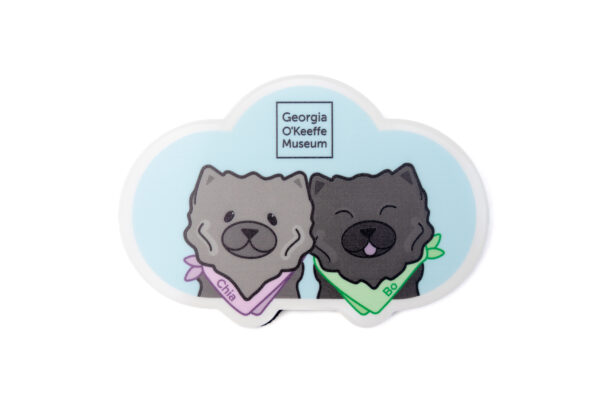 A magnet in the shape of a blue could with two illustrations of dark grey chow chow dogs wearing colorful bandanas marked Bo and Chia