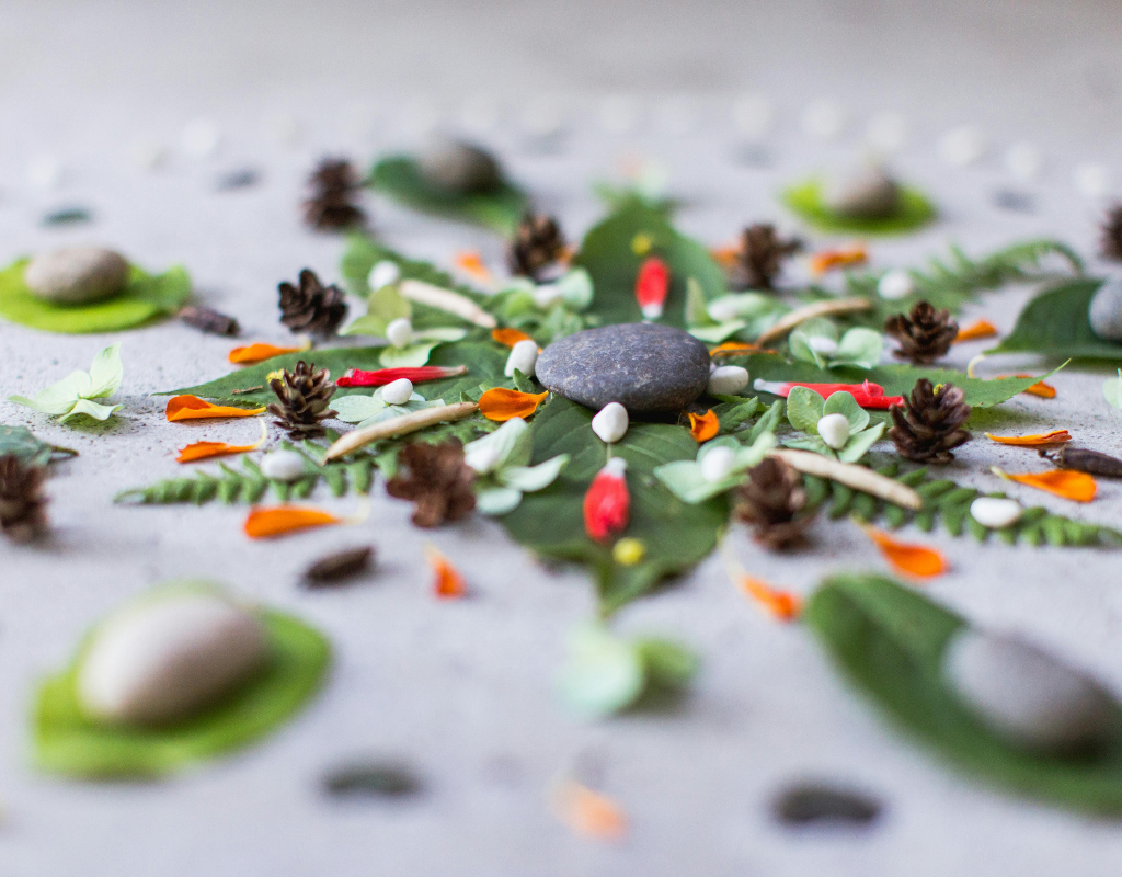 A Mandala made with natural elements such as stones, flowers, pinecones, rocks and leaves.