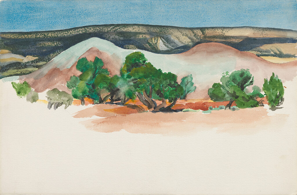 Horizontal watercolor of New Mexico landscape with trees in front of two small hills in the middle ground, while the foreground is unpainted white paper. The background is an expansive vista of a tree-dotted mesa and a clear blue sky.