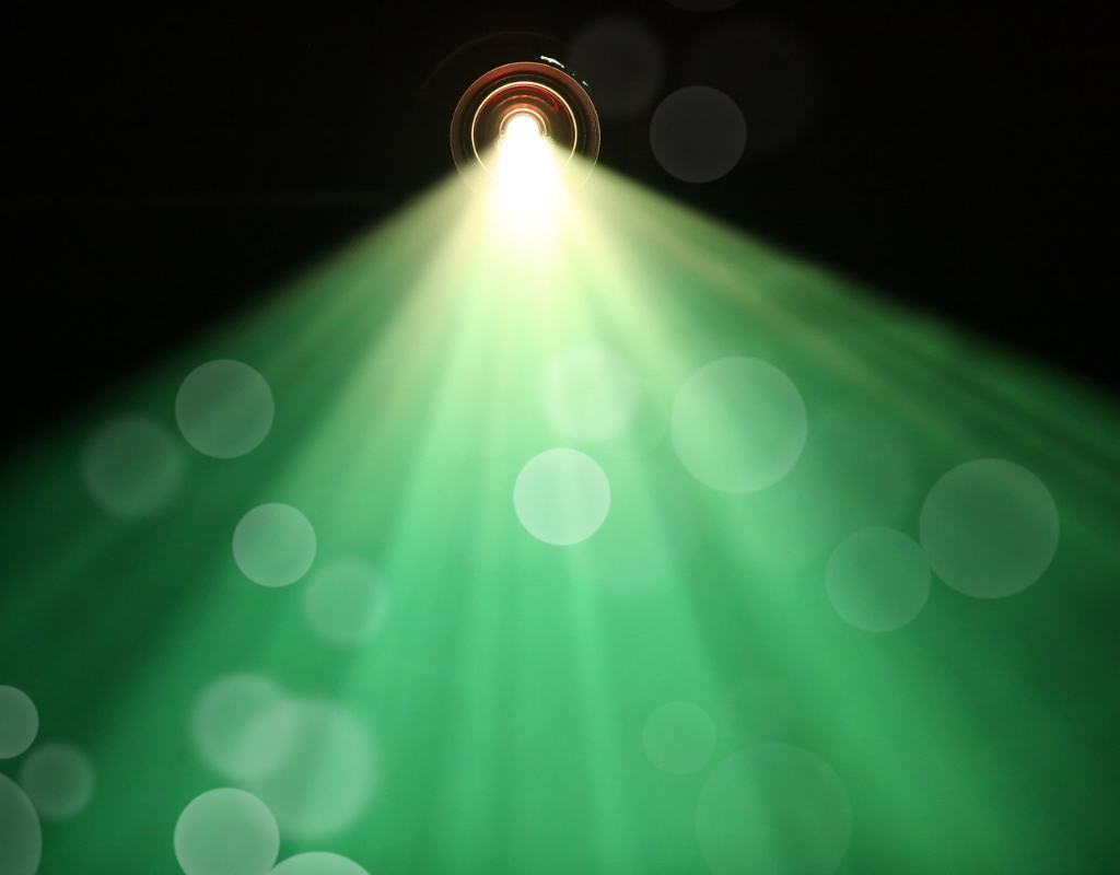 The green and yellow light of a project streams out against a dark background.