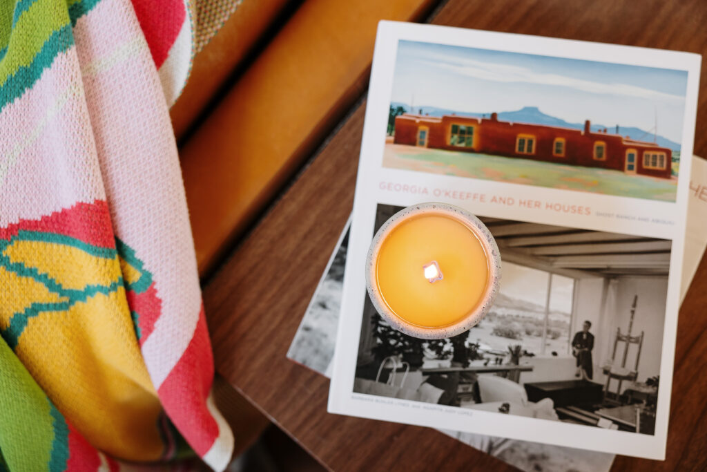 A lit candle is stacked on top of books next to a couch