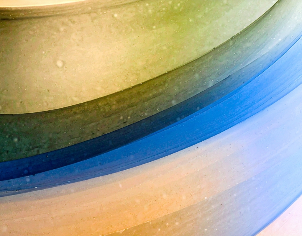 Curved lines of glass in shades of green, blue, and yellow.