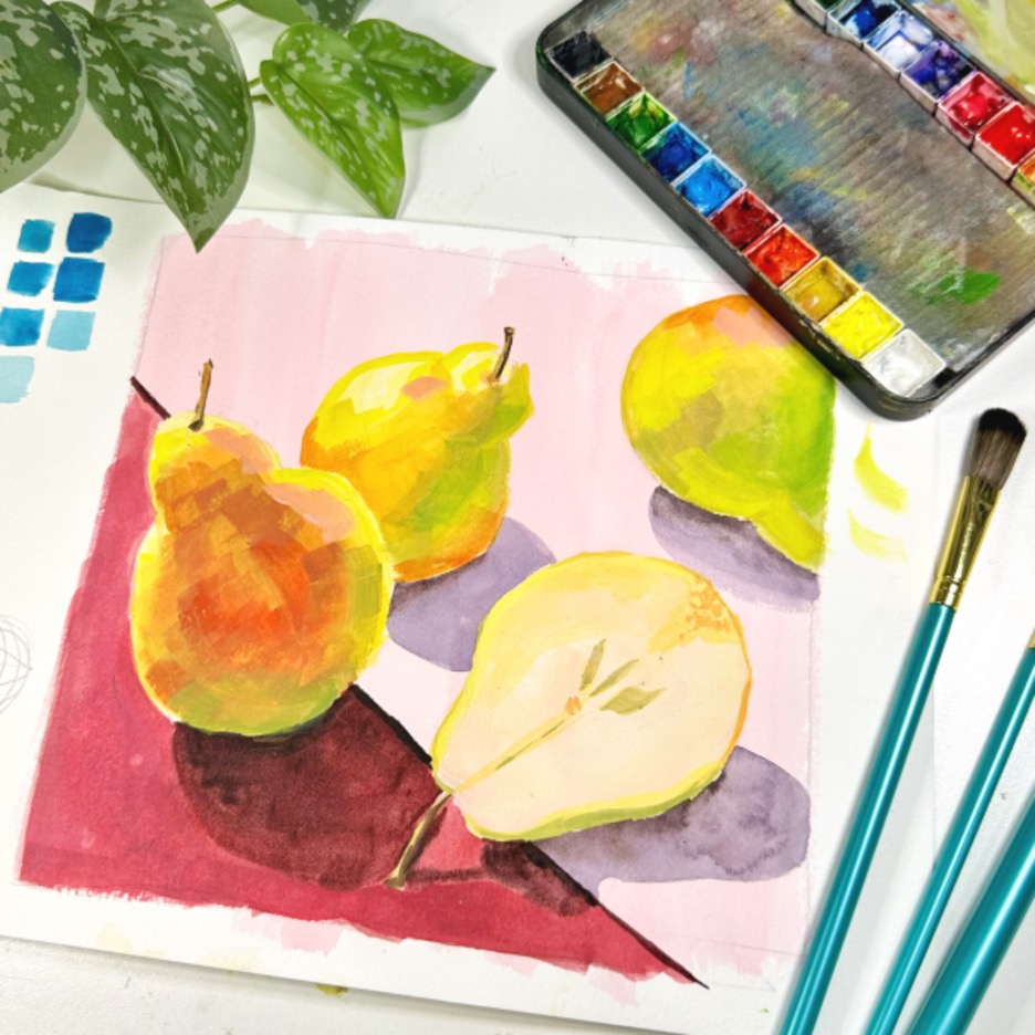 Photograph of a painting of golden pears against a red and pink background. Above the painting are the green leaves of a plant, paintbrushes, and a small paint palette.