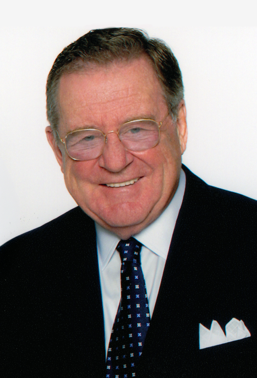 Portrait of a person in glasses and wearing a jacket and tie smiling at the camera.