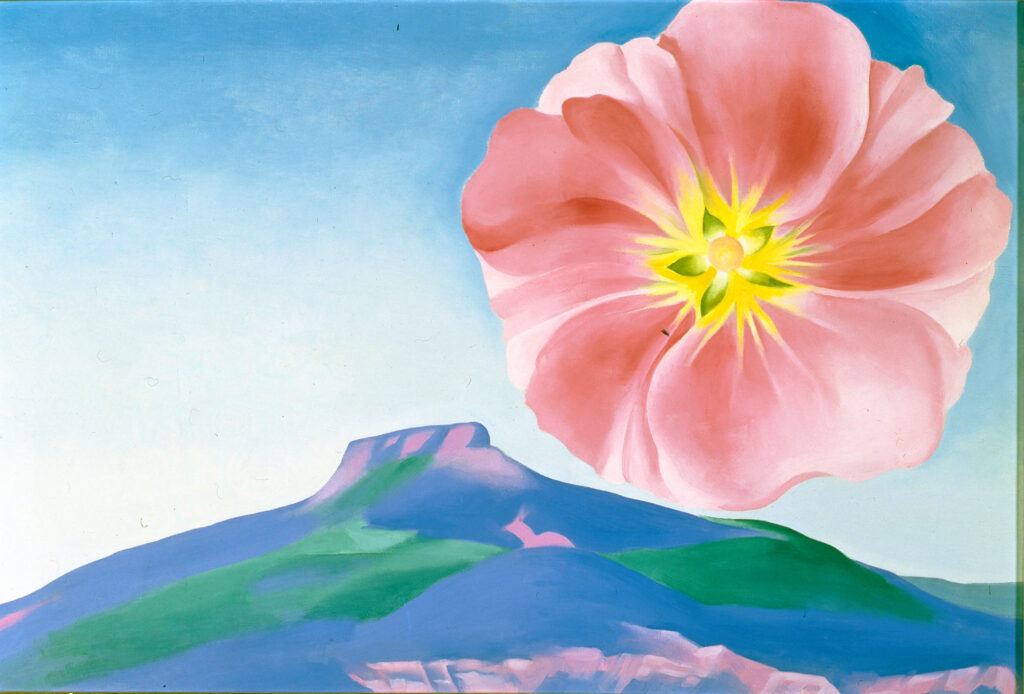 An enlarged, bright pink hollyhock with a yellow center occupies the upper right corner of the work. The flower hovers over a landscape that features a blue, pink, and green rendering of Pedernal below a vast blue sky.