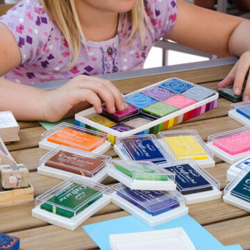 Image of a young person's hands with various stamp ink pads in different colors on a table