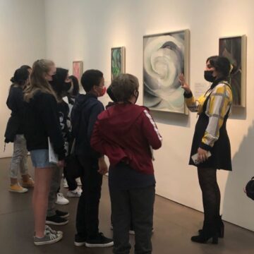 A group of school aged children wearing masks listen to the School Tour coordinator lead a talk.Abstraction Rose