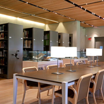 A photograph of the Georgia O'Keefe Museum Research Center. In the foreground there are long tables for viewing archival material. In the background there are collapsible grey archives cases.