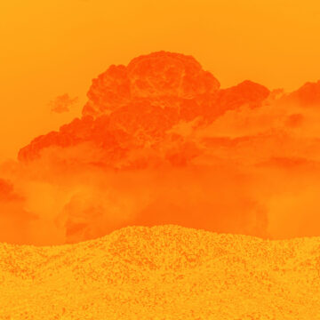 Deep dark orange clouds above the light hills of a desert landscape. The sky behind the cloud is orange and the entire canvas is bathed in orange.