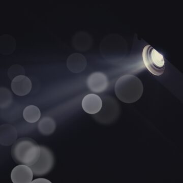 The light coming from the round opening of a projector. Small round circles of light fill the dark background.