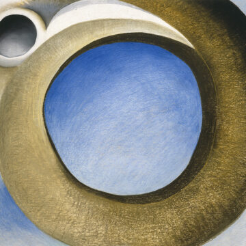 Pastel of a large circular brown goat’s horn. The negative space in the center of the horn and around it are blue. To the left side of the horn is the edge of the goat’s white skull and eye-socket.