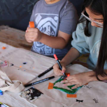 Photograph of two young children using pencils in a creative project.