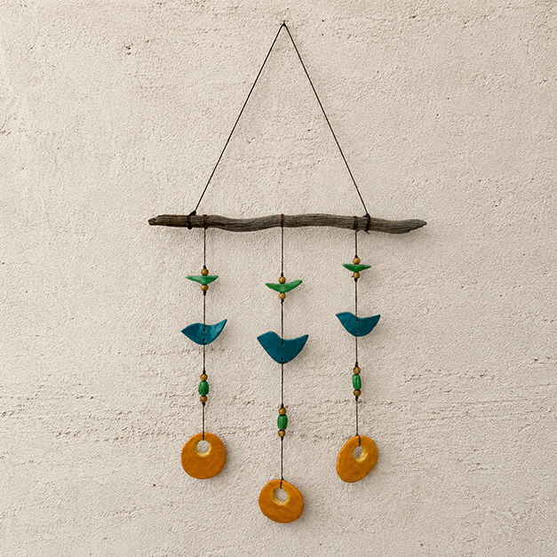 A mobile art piece made of a piece of wood from which hang small circular and bird-shaped pieces of glass.