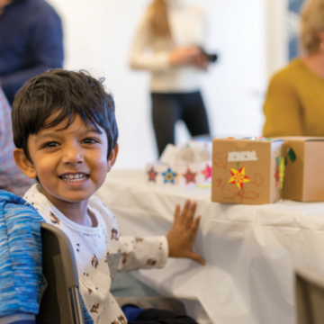 A cute child cheeses at the camera while doing a school art activity at the Georgia O'Keeffe Museum.